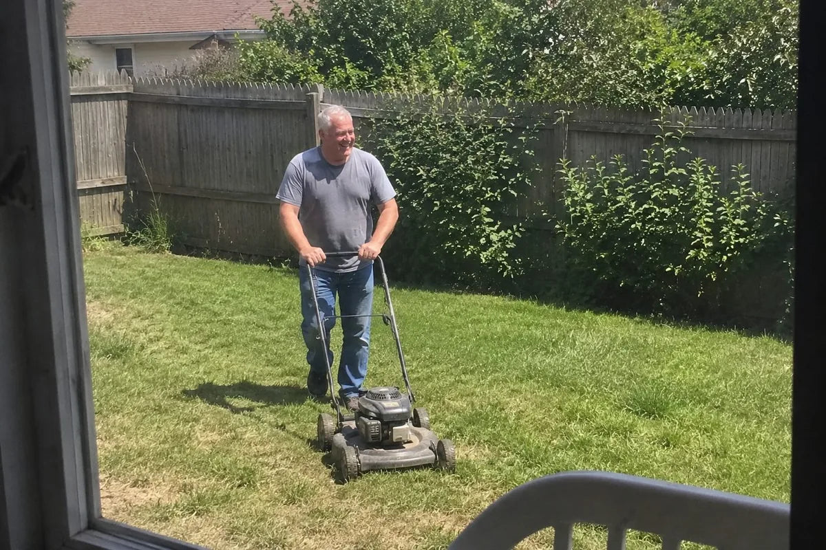 Ray pushing a mower across his backyard at midday, week eight